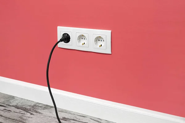 Біла Потрійна Розетка Встановлена Рожевій Стіні Вставленою Чорною Електричною Вилкою — стокове фото