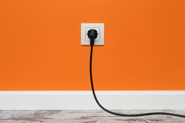 Beyaz priz turuncu duvara monte edilmiş siyah elektrik prizi, ön görüş.