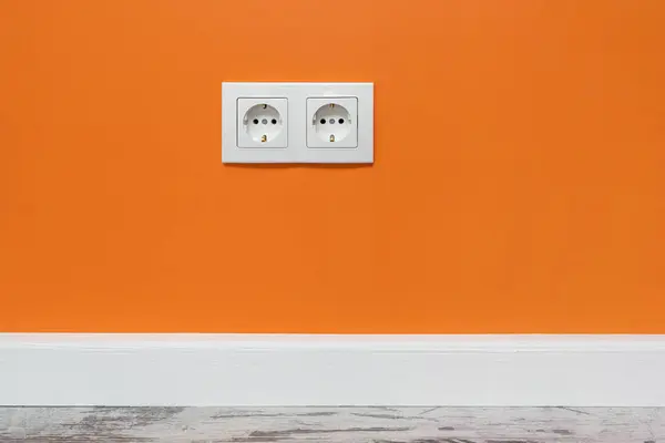 橙色墙上安装了白色双面插座 — 图库照片