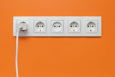 Turuncu duvara monte edilmiş, içine telefon adaptörü yerleştirilmiş, ön manzara..