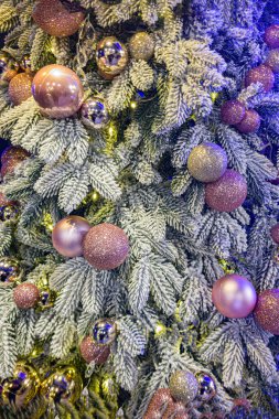Karla kaplı bir Noel ağacının yakın çekimi, parlak ve parlak mor ve altın süslemelerle süslenmiş, bayramların ruhunu somutlaştıran.