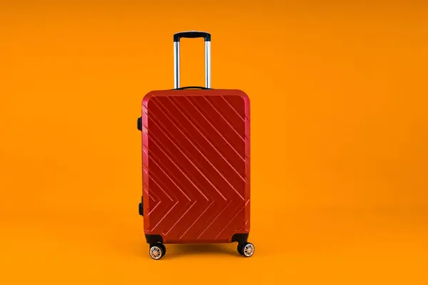 Bold red hard-shell suitcase standing out against a bright yellow background.