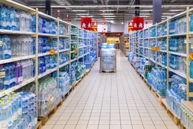 Kyiv, Ukrayna - 03.07.2024: Bir Auchan süpermarketinde, tüketici seçimi ve plastik kullanımını tasvir eden çeşitli şişelenmiş su markalarıyla dolu raflar.