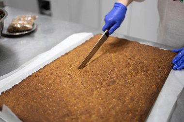 Ev yapımı müsli ve kurutulmuş meyve büfesi hazırlayan ellerin yakın çekimi, malzemeleri ve pişirme sürecini gösteriyor..