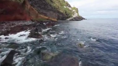 Okyanusun köpüklü suları kayalık sahil feneri boyunca uçan hava manzarası