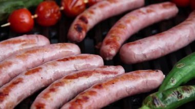 Sosisler ızgarada, sebzeler yakın planda, el yapımı.