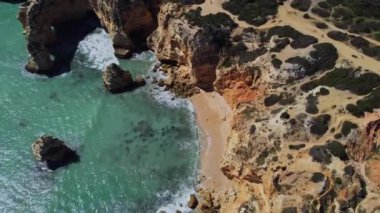 4K Drone - engebeli uçurumlar, kumlu okyanus Ponta Da Piedade. Algarve Bölgesi. Lagos, Portekiz. 15 Nisan 2023
