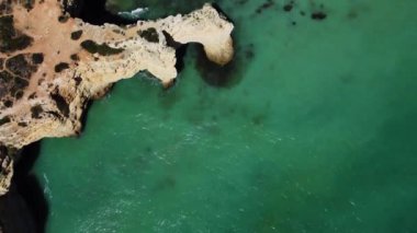 4K Drone - engebeli uçurumlar, kumlu okyanus Ponta Da Piedade. Algarve Bölgesi. Lagos, Portekiz. 15 Nisan 2023