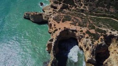 4K Drone - engebeli uçurumlar, kumlu okyanus Ponta Da Piedade. Algarve Bölgesi. Lagos, Portekiz. 15 Nisan 2023