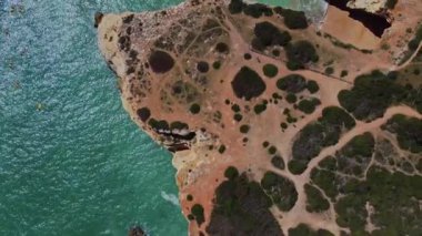 4K İHA. Engebeli kayalık kayalıklar, sahil, kumlu okyanus dalgaları Ponta Da Piedade. Algarve. Portekiz. 20 Nisan 2023