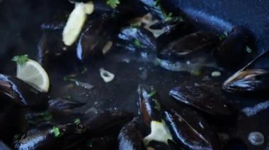 Yemek pişirme, sarımsak ve limonlu midye kızartma tavasında, yakın çekim.