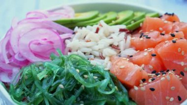 Somon, pirinç, avokado, uyandırma salatası, soğan ve masada daireler çiziyor. Sağlıklı yemek, Asya çiğ yemeği. Geleneksel Hawaii çiğ balık salatası. Japon yemeği..