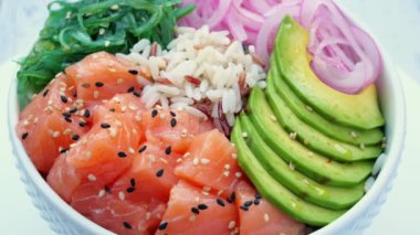 Somon, pirinç, avokado, uyandırma salatası, soğan ve masada daireler çiziyor. Sağlıklı yemek, Asya çiğ yemeği. Geleneksel Hawaii çiğ balık salatası. Japon yemeği..