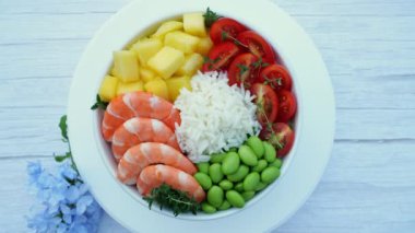 Karides, karides, pilav, edamame fasulyesi, mango, domates, masanın üstünde daireler çizen bir kase. Sağlıklı yemek..
