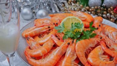 Tabakta kaynamış karides, yılbaşı süsü, bardağa şampanya. Kapat.