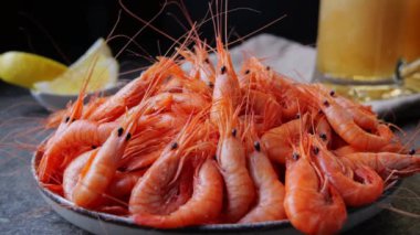 Tabakta pişmiş karides. Bira arka plandan bardakla dökülüyor..