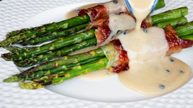 Kızarmış kuşkonmaz, soslu pastırmalı, tabakta.