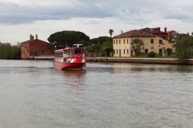 BURANO, İtalya - 29 Nisan 2019: Burano Adası 'ndan bir banliyö teknesi ayrılıyor 
