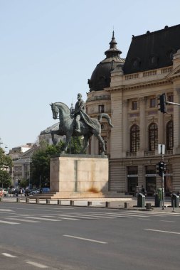 BUCHAREST, ROMANIA - 24 Haziran 2023: Revolutiei Meydanı 'nda (Piata Revolutiei) Kral I. Carol' un binicilik anıtı ile Merkez Üniversitesi Kütüphanesi (Calea Victoriei)
