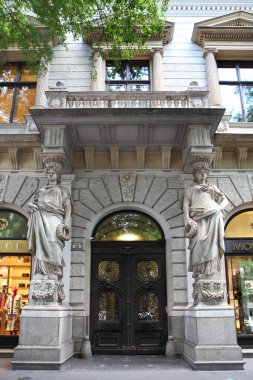 Budapeşte, Macaristan - 3 Temmuz 2018: Budapeşte Caddesi 'ndeki Art Nouveau girişi kadın heykelleri, süsleri ve kahverengi, parmaklıklı bir kapı.