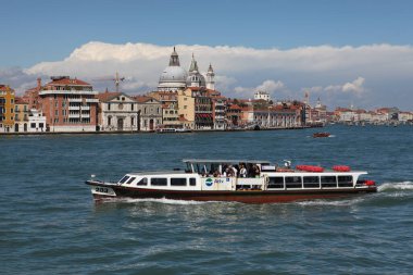 Venedik, İtalya - 27 Nisan 2019: Vaporetto olarak da bilinen bir su otobüsü, St. Mark 's Campanile' den geçerken Venedik gölünde yelken açıyor..