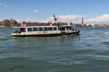 Venedik, İtalya - 27 Nisan 2019: Vaporetto olarak da bilinen bir su otobüsü, St. Mark 's Campanile' den geçerken Venedik gölünde yelken açıyor..