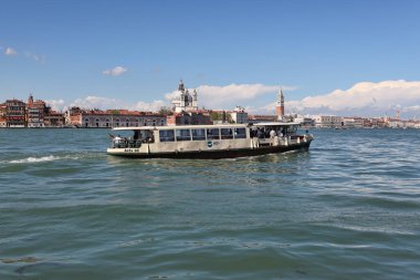Venedik, İtalya - 27 Nisan 2019: Vaporetto olarak da bilinen bir su otobüsü, St. Mark 's Campanile' den geçerken Venedik gölünde yelken açıyor..