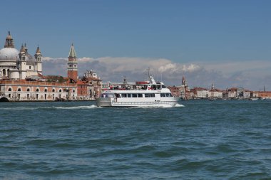Venedik, İtalya - 27 Nisan 2019: Küçük beyaz bir yolcu gemisi Venedik 'in pitoresk mimarisini geçerek Büyük Kanal boyunca seyahat ediyor.
