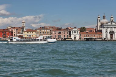 Venedik, İtalya - 27 Nisan 2019: Küçük beyaz bir yolcu gemisi Venedik 'in pitoresk mimarisini geçerek Büyük Kanal boyunca seyahat ediyor.