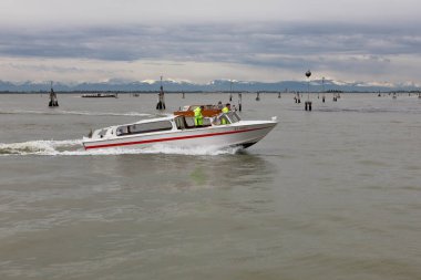 Venedik, İtalya - 29 Nisan 2019: Arkasında karla kaplı dağlar olan Venedik lagünündeki bir motorlu tekne ambulansı.