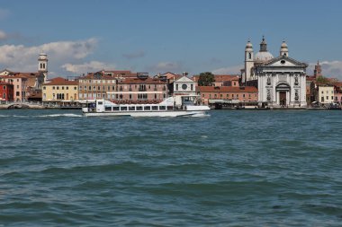 Venedik, İtalya - 27 Nisan 2019: Küçük beyaz bir yolcu gemisi Venedik 'in pitoresk mimarisini geçerek Büyük Kanal boyunca seyahat ediyor.