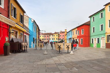 BURANO, İtalya - 29 Nisan 2019: Burano Adası Venedik yakınlarındaki parlak renkli binaları ve büyüleyici butik dükkanlarıyla ünlü popüler bir turizm merkezi..