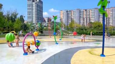 Dnipro, Ukraine-August 19, 2022: Children bathe and play in public fountain during sweltering summer heat. Families with children have a rest in city park in play area for children.