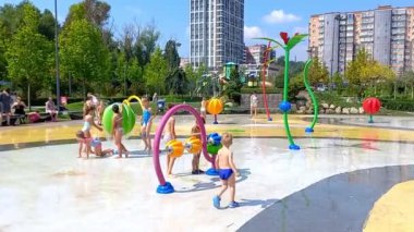 Dnipro, Ukraine-August 19, 2022: Children bathe and play in public fountain during sweltering summer heat. Families with children have a rest in city park in play area for children.
