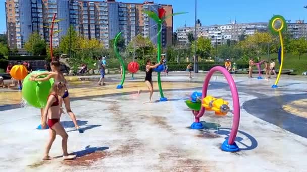 ウクライナのドニプロ 2022年8月7日 子供たちは夏の暑さの中 公衆噴水で入浴して遊ぶ 子供を持つ家族は子供のための遊び場で都市公園で休息をしています 女の子は滑り落ちて — ストック動画