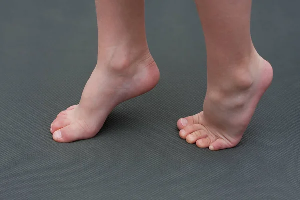 子供はマットの上で裸足だ 子供は足の運動をしつま先に立っています 子供の平らな足の予防 — ストック写真