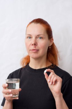 Üst dudağında uçuk olan orta yaşlı bir kadının portresi. Elinde hap ve bir bardak su tutan bir kadın. HSV 'den kaynaklanan enfeksiyon kapmış yüz. Dermatoloji. İlaç..