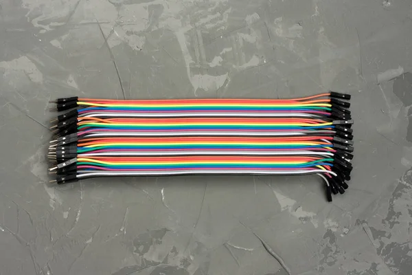 Arduino için erkek kadına atlama kablosu. Gri arkaplandaki renkli bağlantı kabloları. Mikro denetleyicilerin güvenilir bağlantıları ve programlanması için modülleri ve sensörleri bağlamak için kablolar