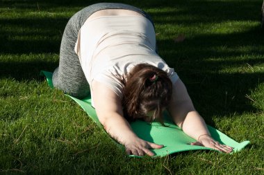 Fitness, açık hava eğitimi, kilo kaybı. Şişman kadın doğada egzersiz yapıyor. Kilolu orta yaşlı kadın şehir parkında pilates yapıyor. Sağlıklı yaşam tarzı