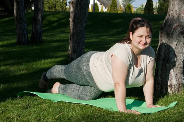 Fitness, outdoor training, weight loss. Fat woman doing exercises in nature. overweight middle-aged woman does Pilates in city park. Healthy lifestyle