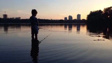 Çocuk gün batımında nehir kıyısından olta ile balık yakalıyor. Anaokulu çocuğu balık tutuyor, dizlerine kadar suya batmış. Sıcak bir yaz akşamı, küçük balıkçı, mutlu bir çocukluk, en sevdiği hobi balık tutmaktır.