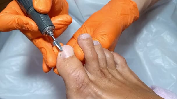 在温泉沙龙里做硬体医疗修脚手术的妇女 专业的脚趾护理 用一种特殊的修指甲和修脚装置来处理脚趾上的钉子 黄手套大师 — 图库视频影像