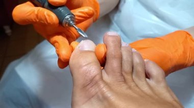 Spa salonunda nalbur pedikür yapan bir kadın. Profesyonel ayak parmağı bakımı. Tırnakların manikür ve pedikür için özel bir aletle tedavi edilmesi. Güzellik endüstrisinde iş