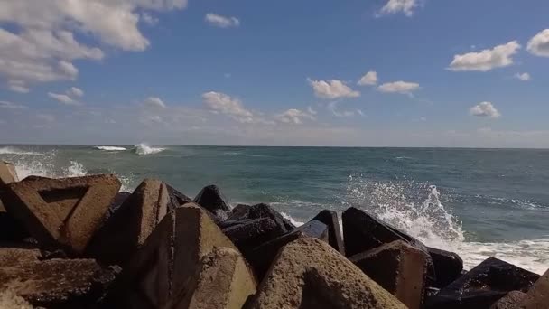 海浪冲撞近岸的石堤 浪花洒在海里的码头上 海上刮起了新鲜的风 波涛汹涌的大海飘扬着长长的浪花 夏日阳光灿烂的户外海景 — 图库视频影像
