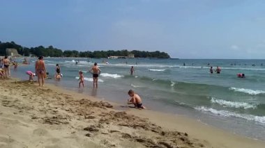 Kiten, Bulgaristan - 13 Haziran 2024: Turistler yaz günü güneşleniyor ve denizde yüzüyorlar. Kumda oynayan çocuklar kumdan kaleler inşa ederler. Bulgaristan 'ın Karadeniz kıyısında tatil.