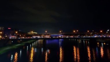 Gece şehri. Polonya 'nın Krakow kentindeki Vistula Nehri üzerindeki köprü manzarası. Fenerlerin ışıkları suya yansır. Akşamları köprü trafiği yoğun olur. İş çıkışı