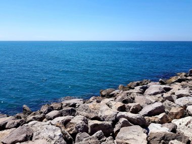 Güneşli bir günde kayalar ve mavi denizle kaplı bir deniz manzarası..