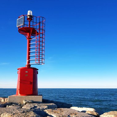 Deniz kıyısındaki kırmızı deniz feneri mavi gökyüzünün arka planında