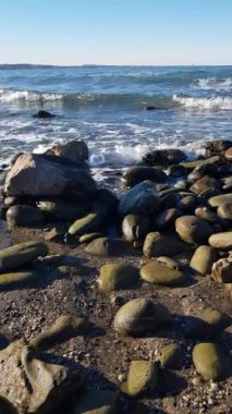 Deniz dalgaları kıyıdaki taşlara çarpıyor.