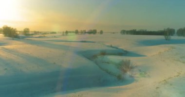 Soğuk kış kutup bölgesinin insansız hava görüntüsü, ufukta karla kaplı ağaçlar, buz nehri ve güneş ışınları. Aşırı düşük sıcaklık havası. Sibirya